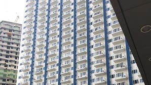 A high-rise residential building with multiple balconies and a swimming pool in the foreground.