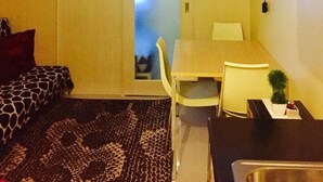A compact room with a bed, a desk, a chair, and a small table.
