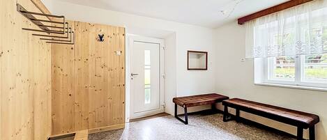 A room with a wooden wall, a bench, a door, and a window.