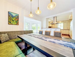 A modern kitchen with a central island, pendant lighting, and a dining area with a bench. - Chalet Jana by Interhome (Feichten im Kaunertal)