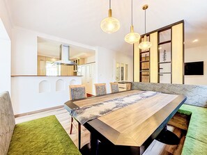 A modern kitchen with a large island, pendant lighting, and a dining area with a long table. - Chalet Jana by Interhome (Feichten im Kaunertal)