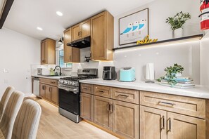 A modern kitchen with wooden cabinets, stainless steel appliances, and a built-in oven. - Modern & Spacious Anaheim Home 7 Min to Disneyland Game Room Theater Sleeps 14 (Anaheim)