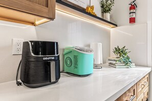 Eine Küchenarbeitsfläche mit Kaffeemaschine, Mixer und Feuerlöscher.