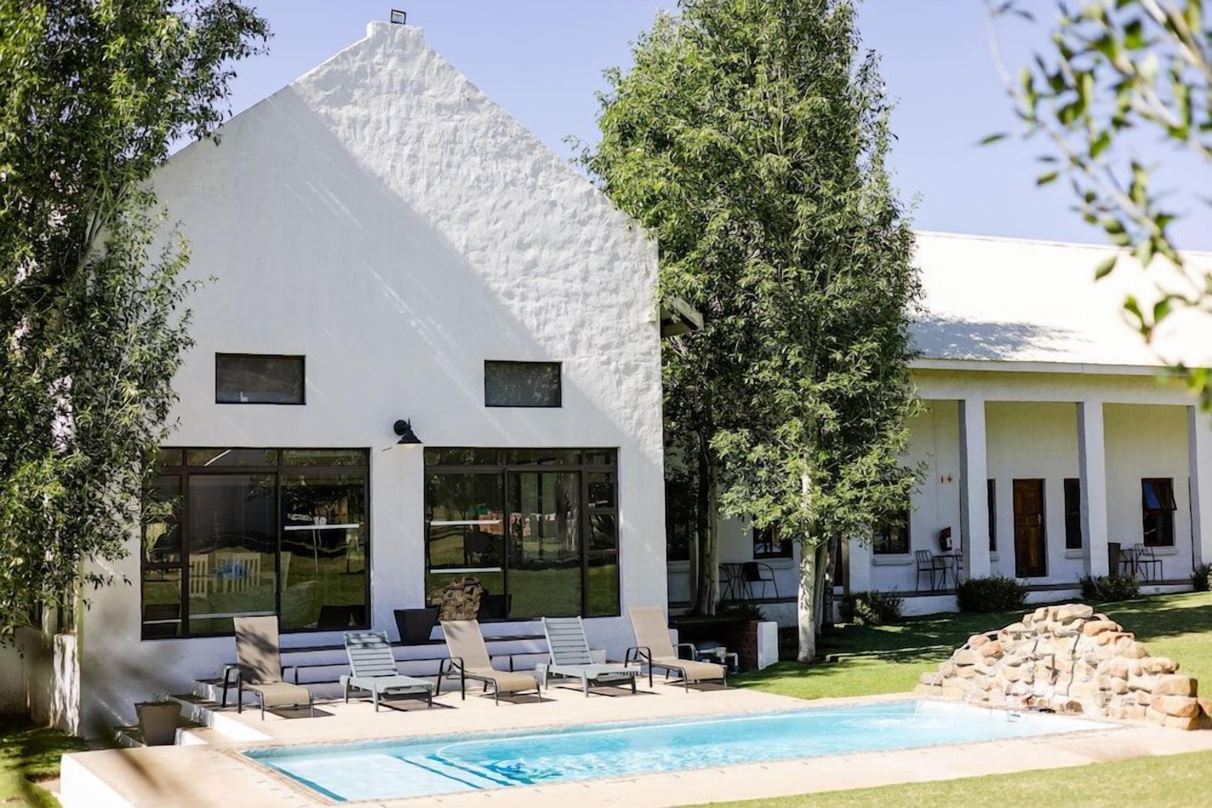 A modern white building with a pool and lounge chairs.