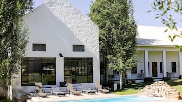 A modern white building with a pool and lounge chairs.