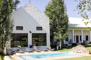 A modern white building with a pool and lounge chairs.