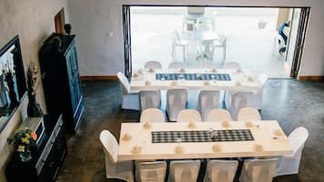 A dining area with multiple tables and chairs, a television mounted on the wall, and a view of the outdoors.