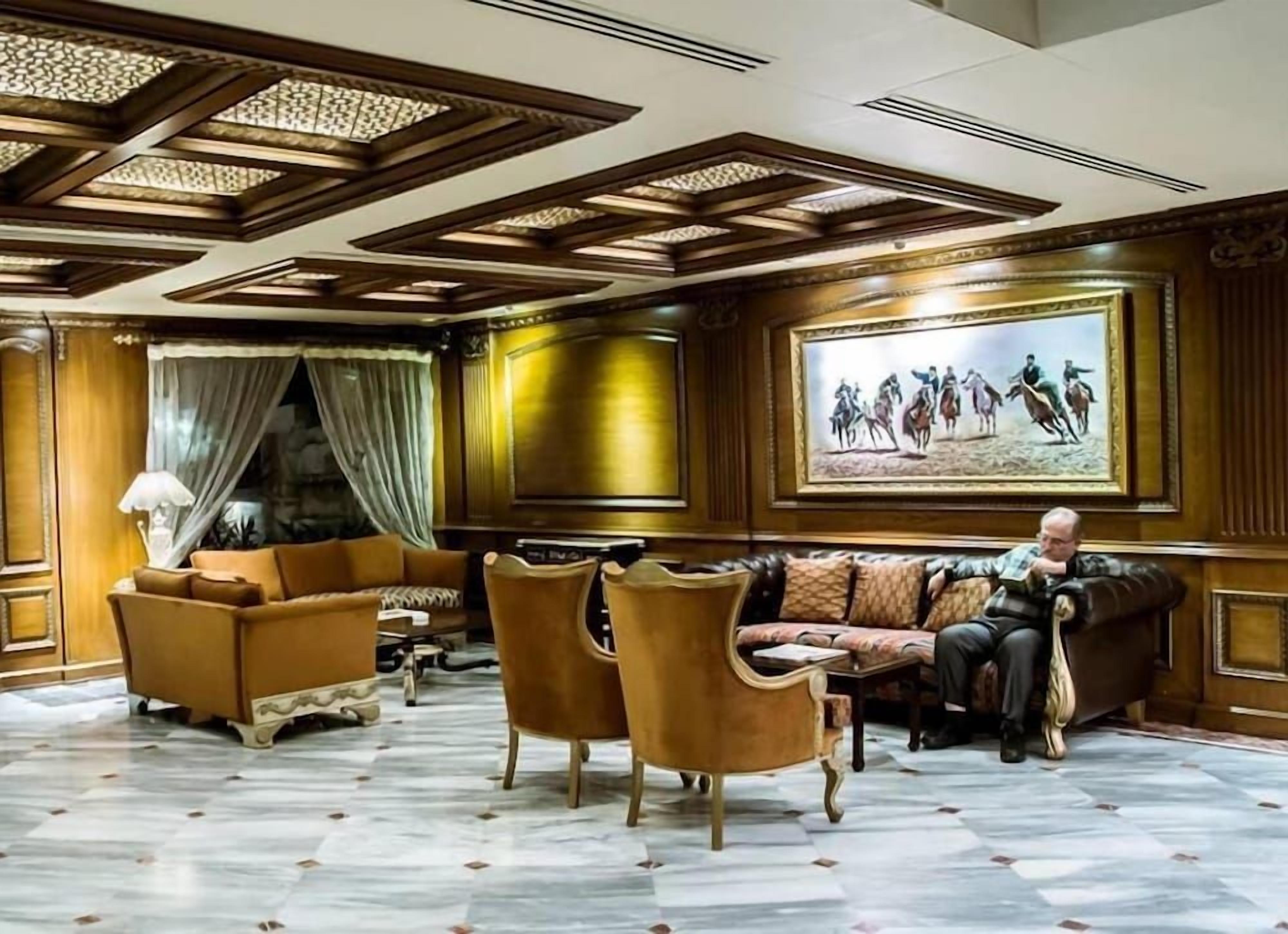A lobby with a patterned floor, a sofa set, and a painting on the wall.