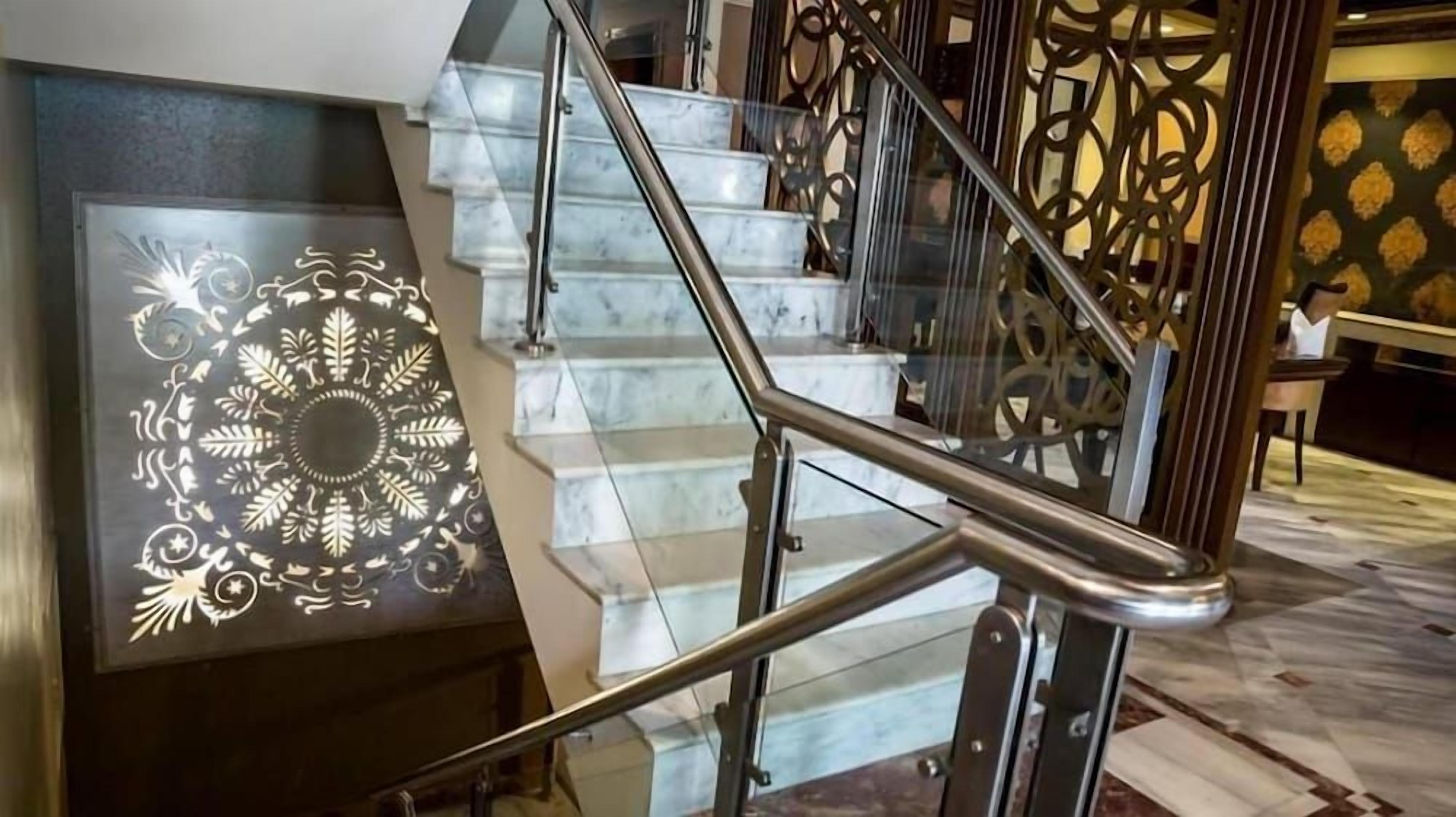 A staircase with a glass railing and a decorative wall panel.