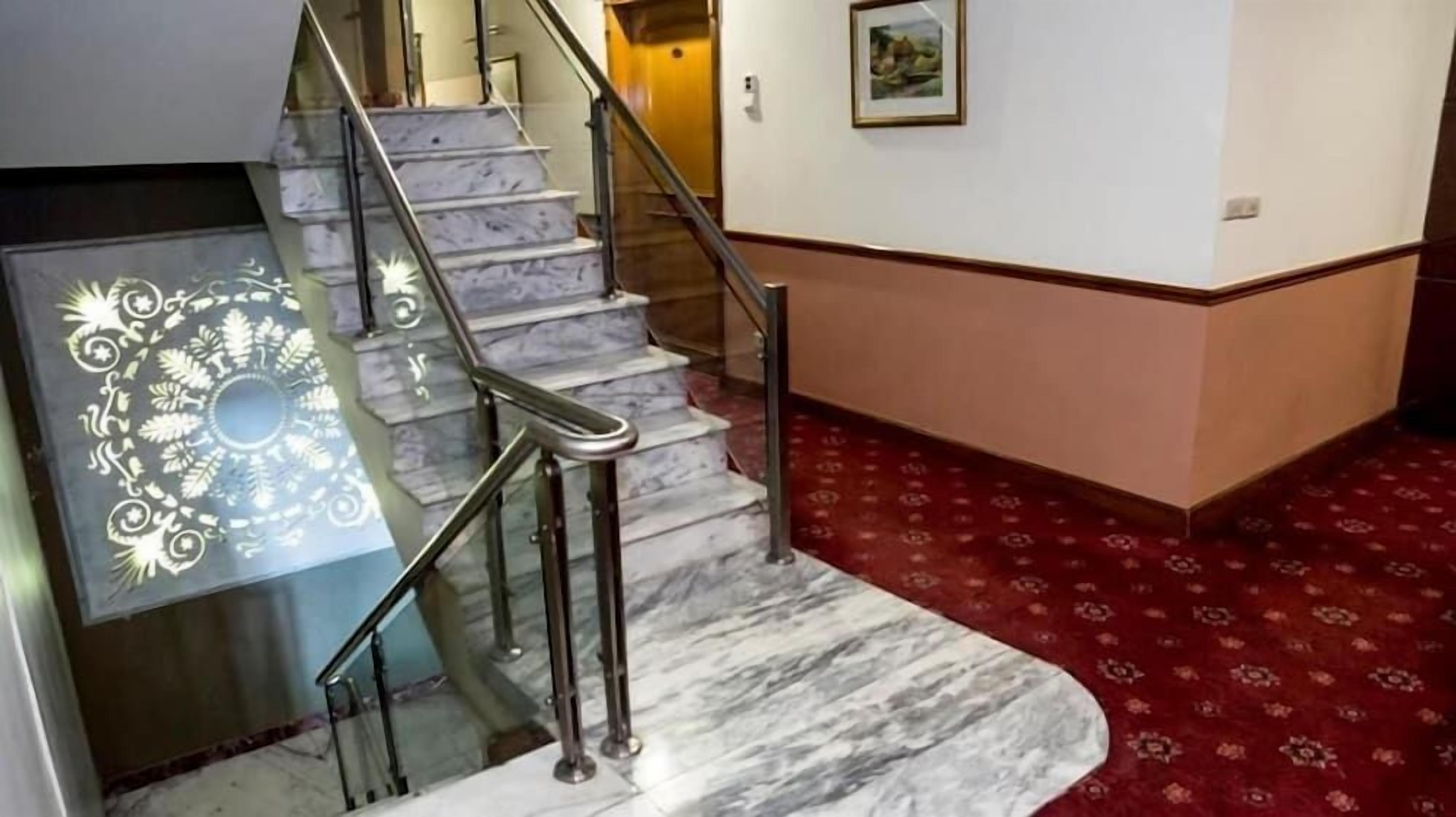 Una escalera de mármol con barandillas de metal que conduce a una plataforma.