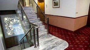 Un escalier en marbre avec des rampes métalliques menant à un palier.