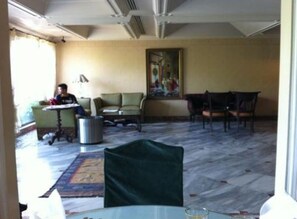 A hotel room with a dining area, a green chair, a table, and a painting on the wall. - Regency Inn Hotel Lahore (Lahore)