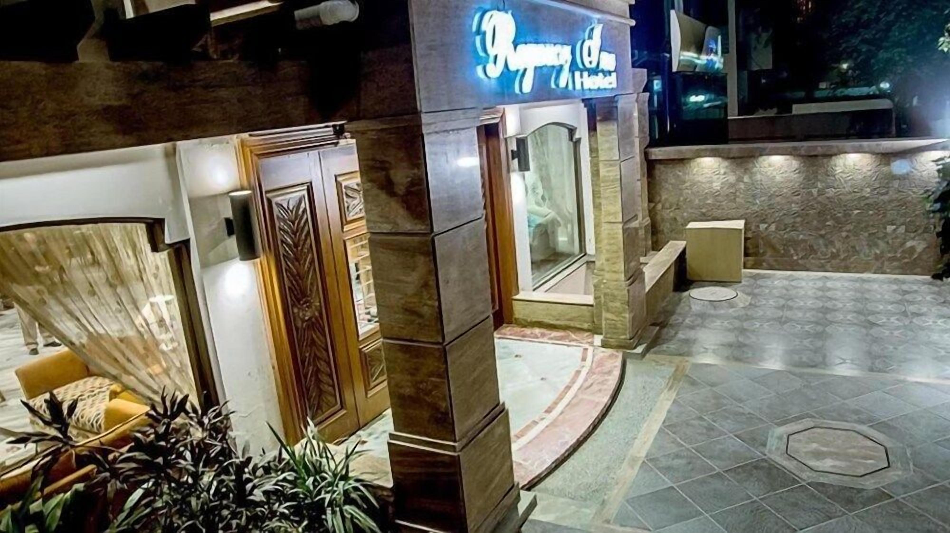A hotel entrance with a reception desk, a glass door, and a stone facade.
