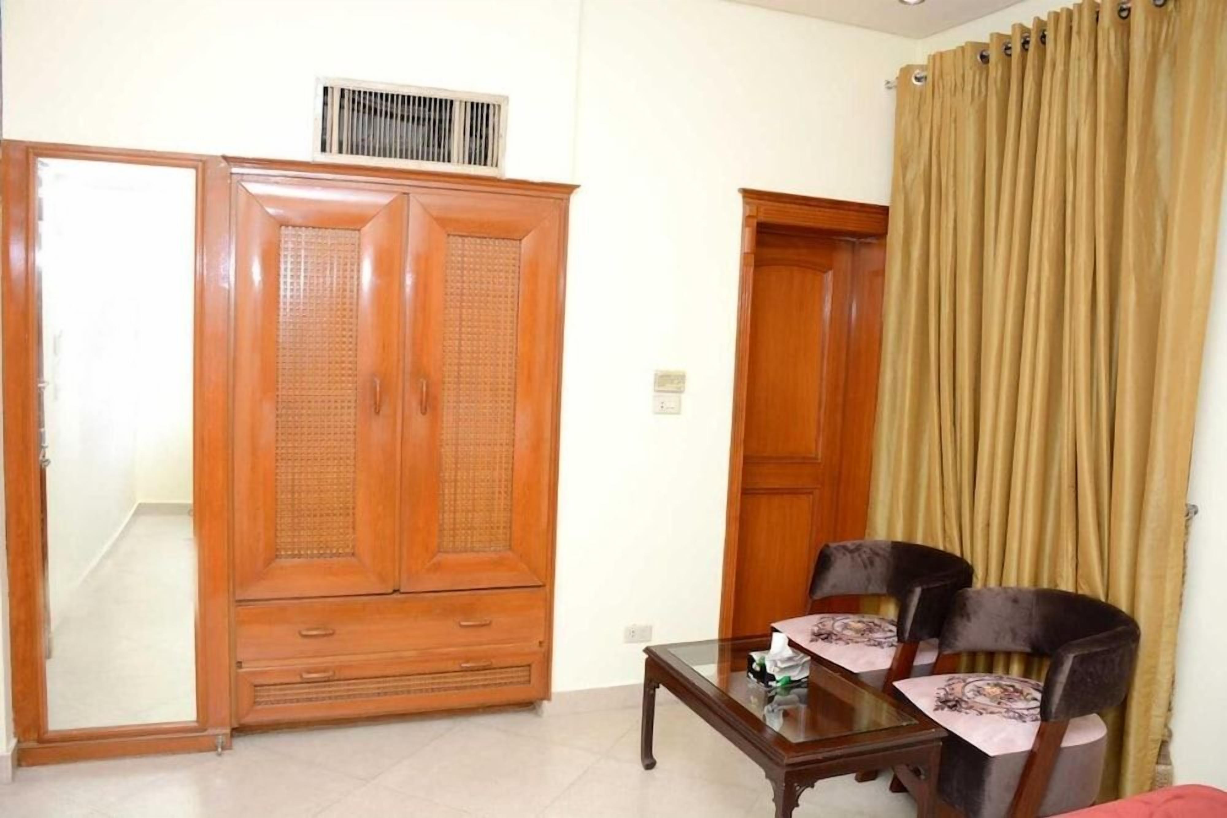 A room with a wooden wardrobe, a table with chairs, and a curtain.