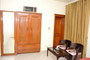 A room with a wooden wardrobe, a table with chairs, and a curtain. - Regency Inn Hotel Lahore (Lahore)
