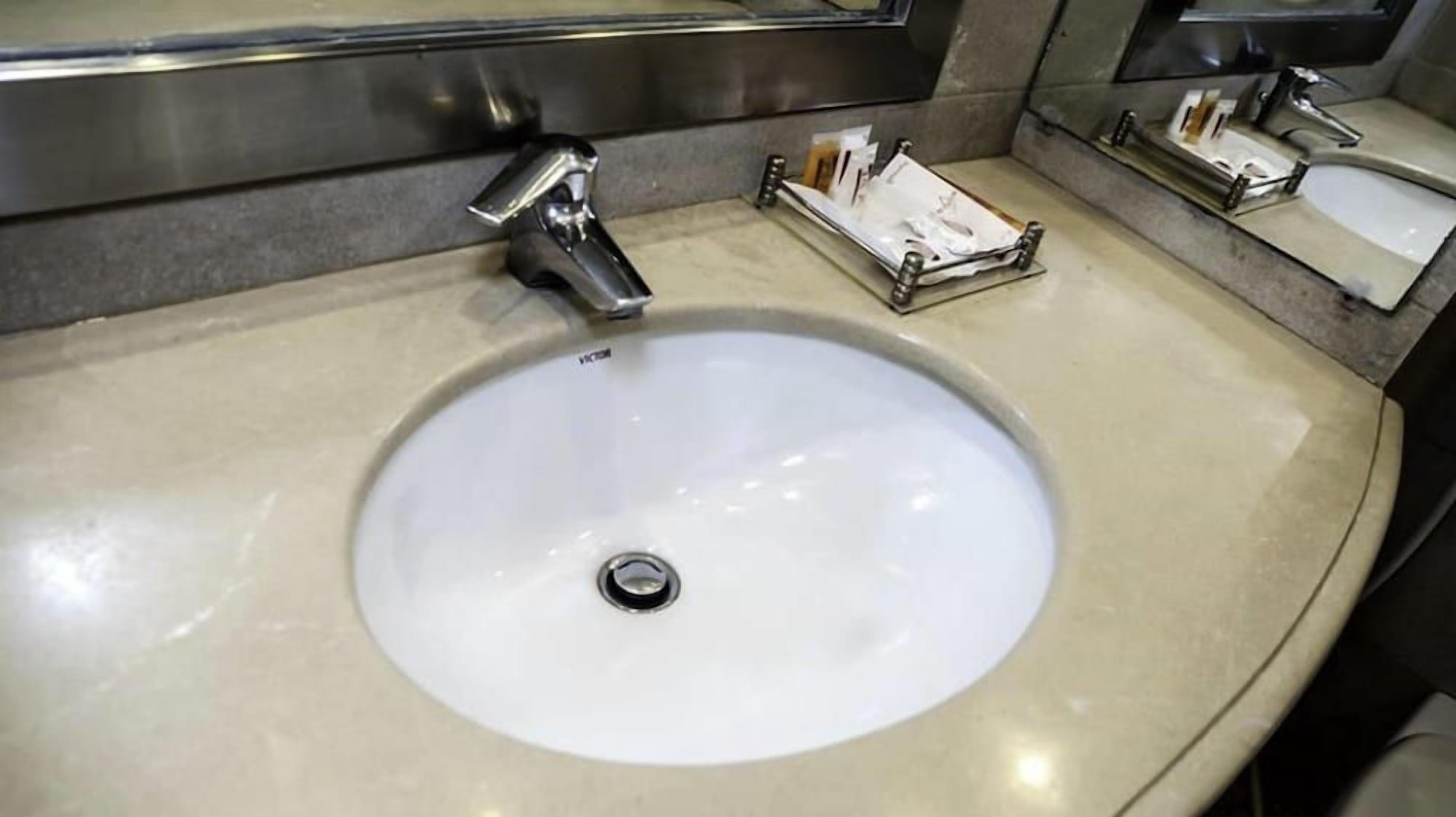 A bathroom sink with a chrome faucet, a mirror above it, and a soap dish on the countertop.