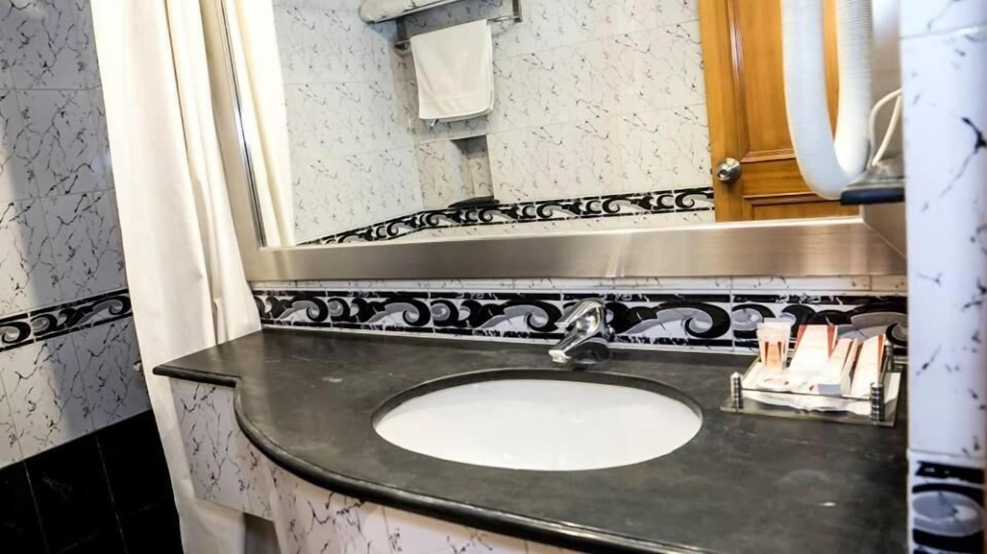 A bathroom with a marble sink, a mirror, and a towel rack.