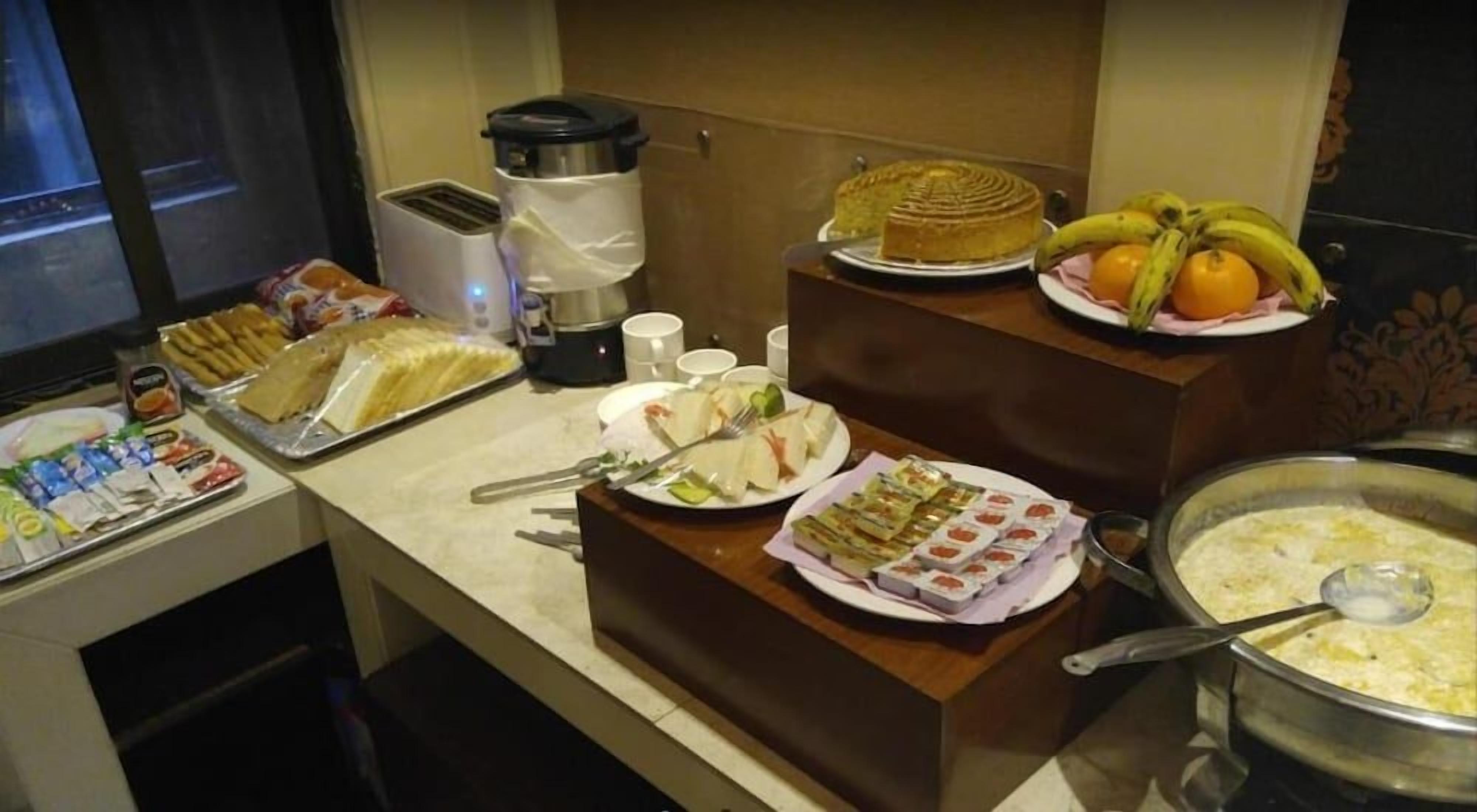 Un buffet proposant une variété de plats, notamment des sandwichs, des fruits et un grand récipient rempli de soupe.