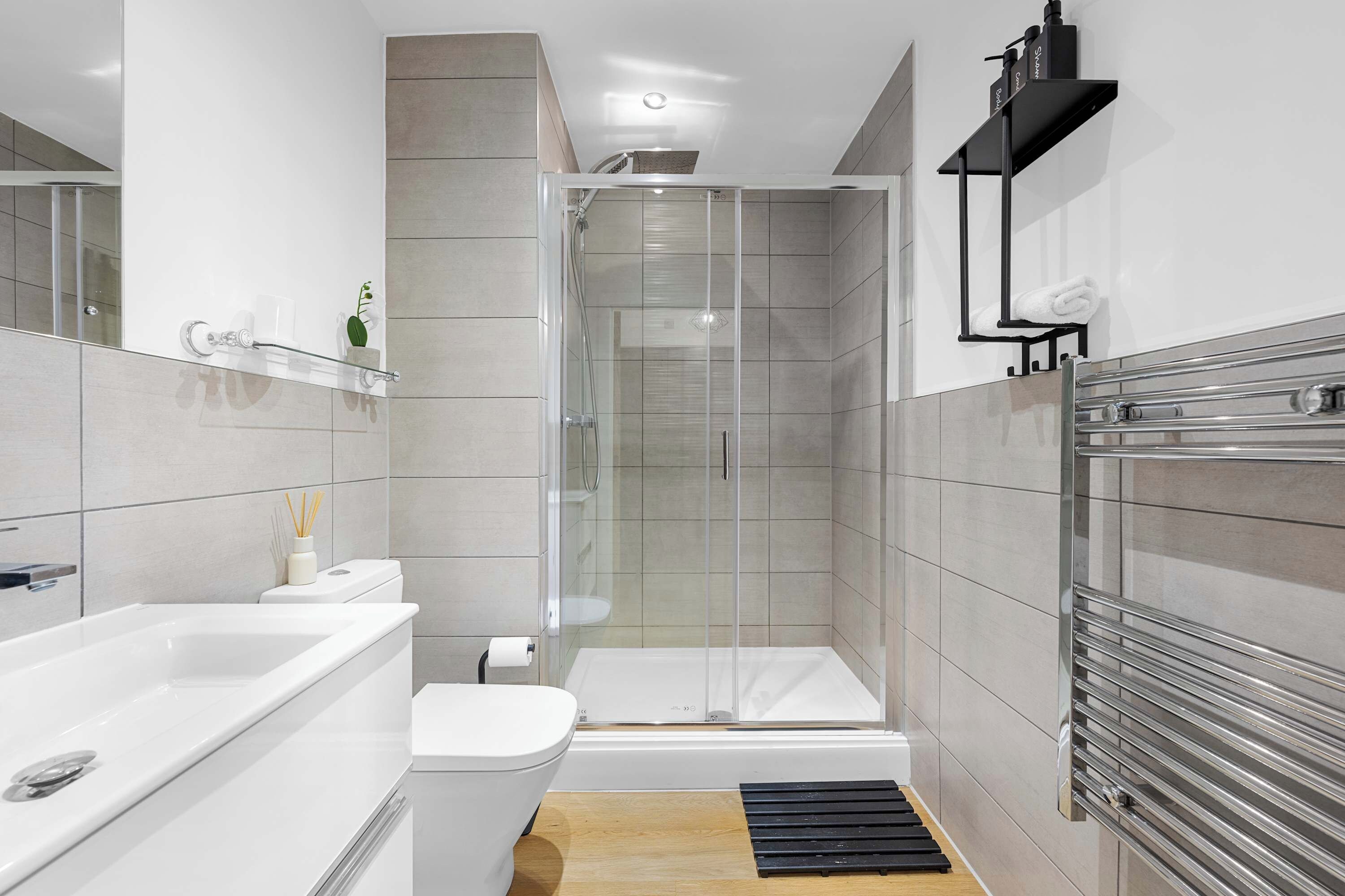 Et stilfuldt badeværelse med en brusekabine i glas, et hvidt badekar og et toilet.