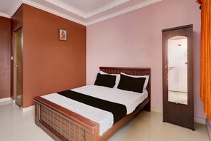 Ein Schlafzimmer mit einem hölzernen Bett, einer Tür mit Spiegel und einer kleinen Wanddekoration.
