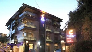 A multi-story hotel with balconies, a gated entrance, and a sign indicating it offers rooms, cottages, and a restaurant. - Silver Arch Hotel (Dehradun)