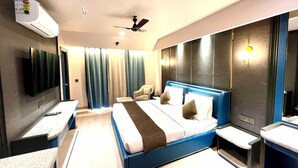 A modern hotel room with a large bed, a flat-screen TV, a desk, and a bathroom with a mirror and sink. - Silver Arch Hotel (Dehradun)