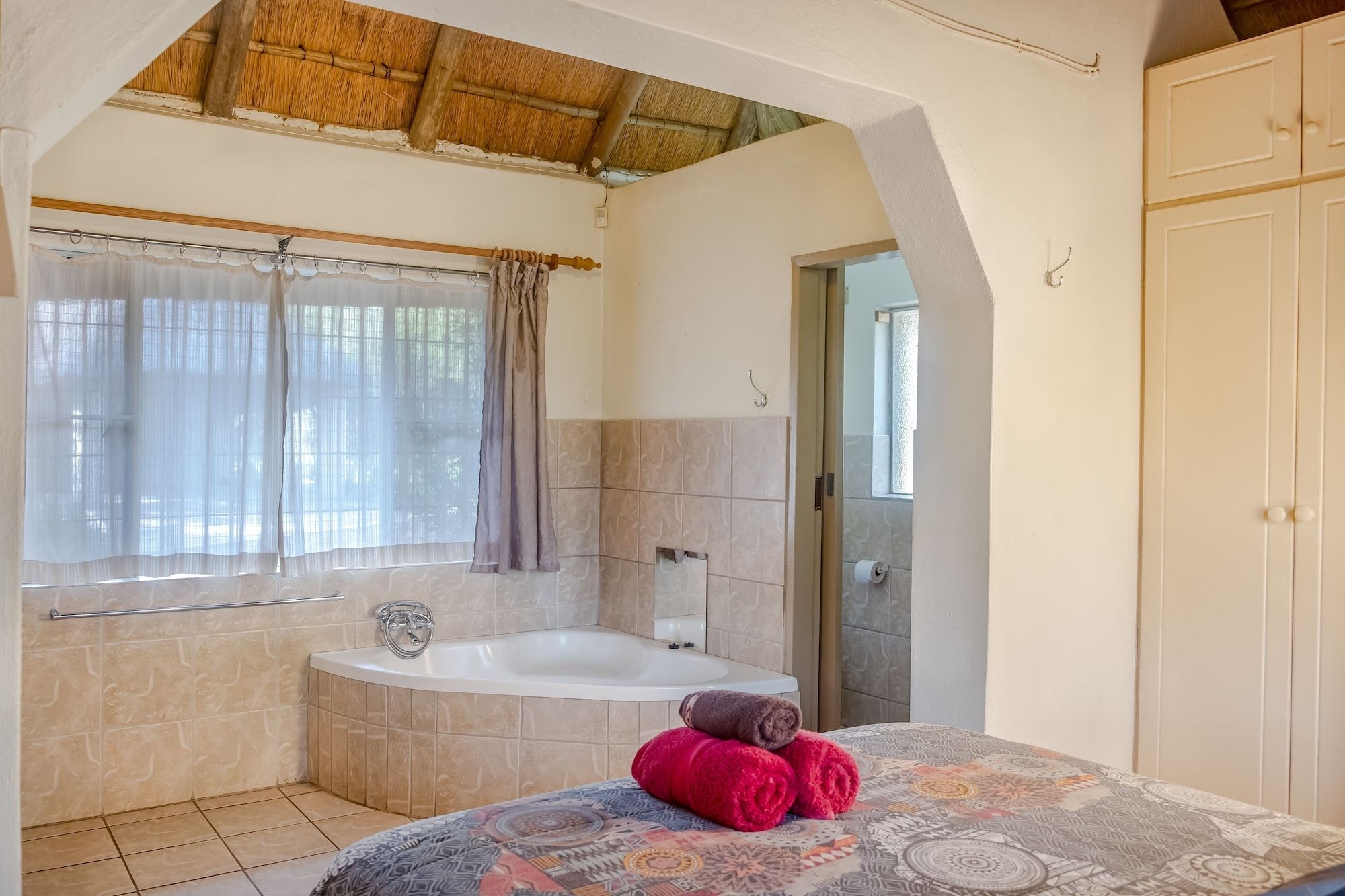 A bathroom with a bathtub, a towel rack, and a patterned shower curtain.