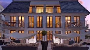 Un edificio de dos plantas con balcones, ventanas amplias y zonas de estar al aire libre.