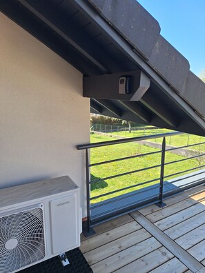 A balcony with a view of a grassy area, a metal railing, and an air conditioning unit. - La Montagnette - With a terrace and mountain views (Entrelacs)