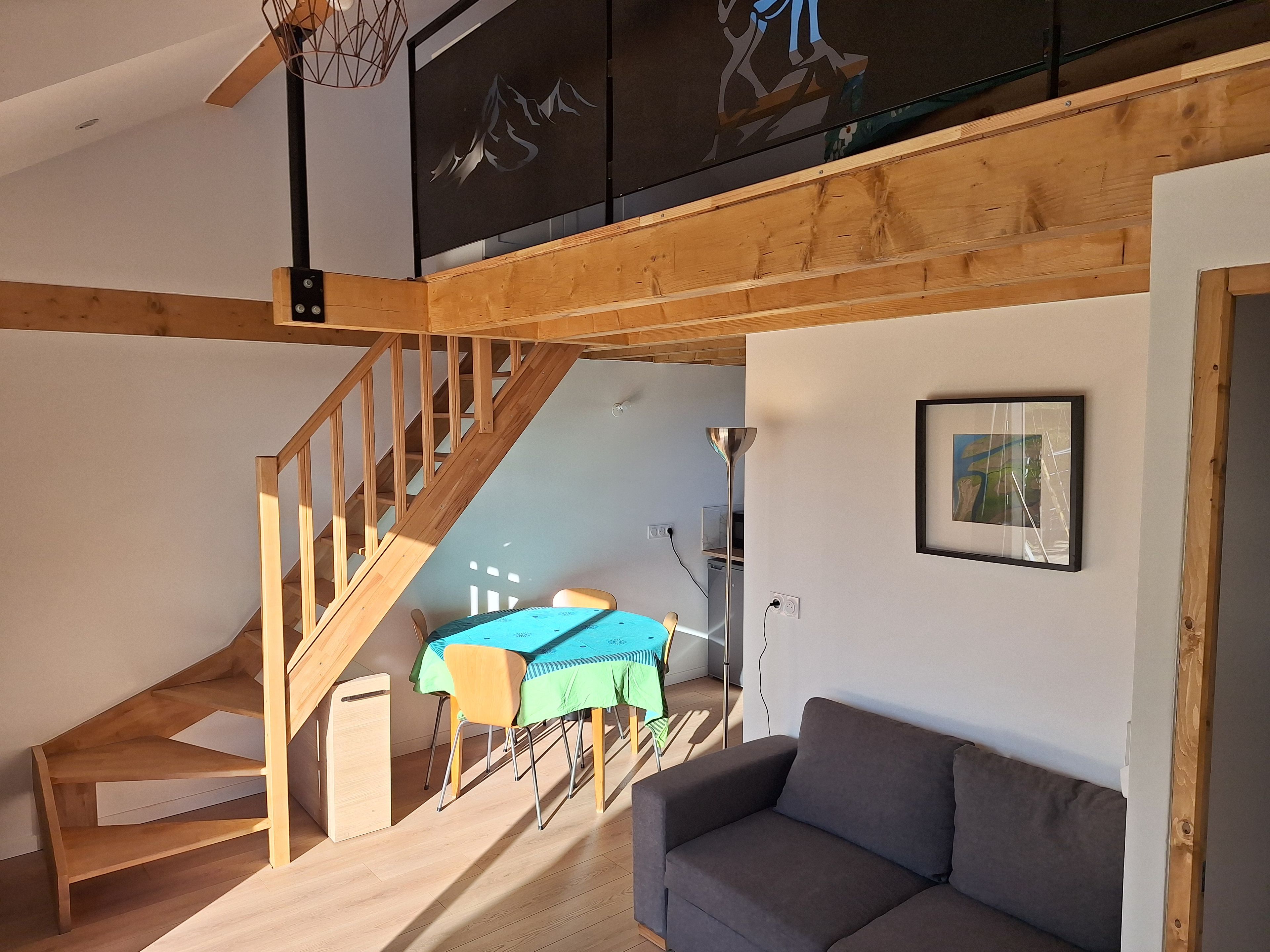 Ein geräumiger Wohnbereich mit einer Treppe zu einer oberen Ebene, einem Esstisch mit Stühlen und einem Sofa.