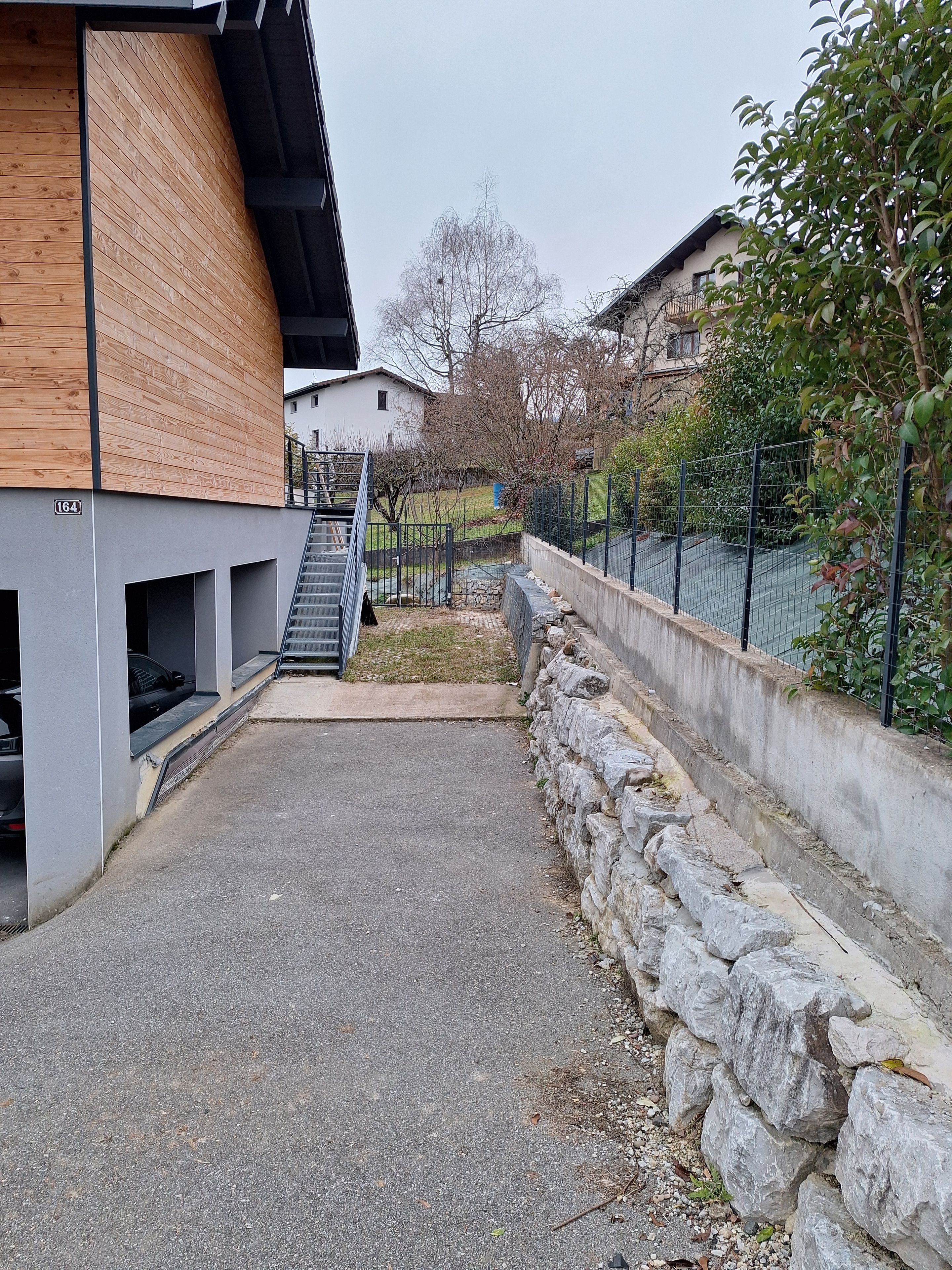 Ein modernes Gebäude mit einer Holzfassade, einer Steinmauer und einem gepflasterten Innenhof.