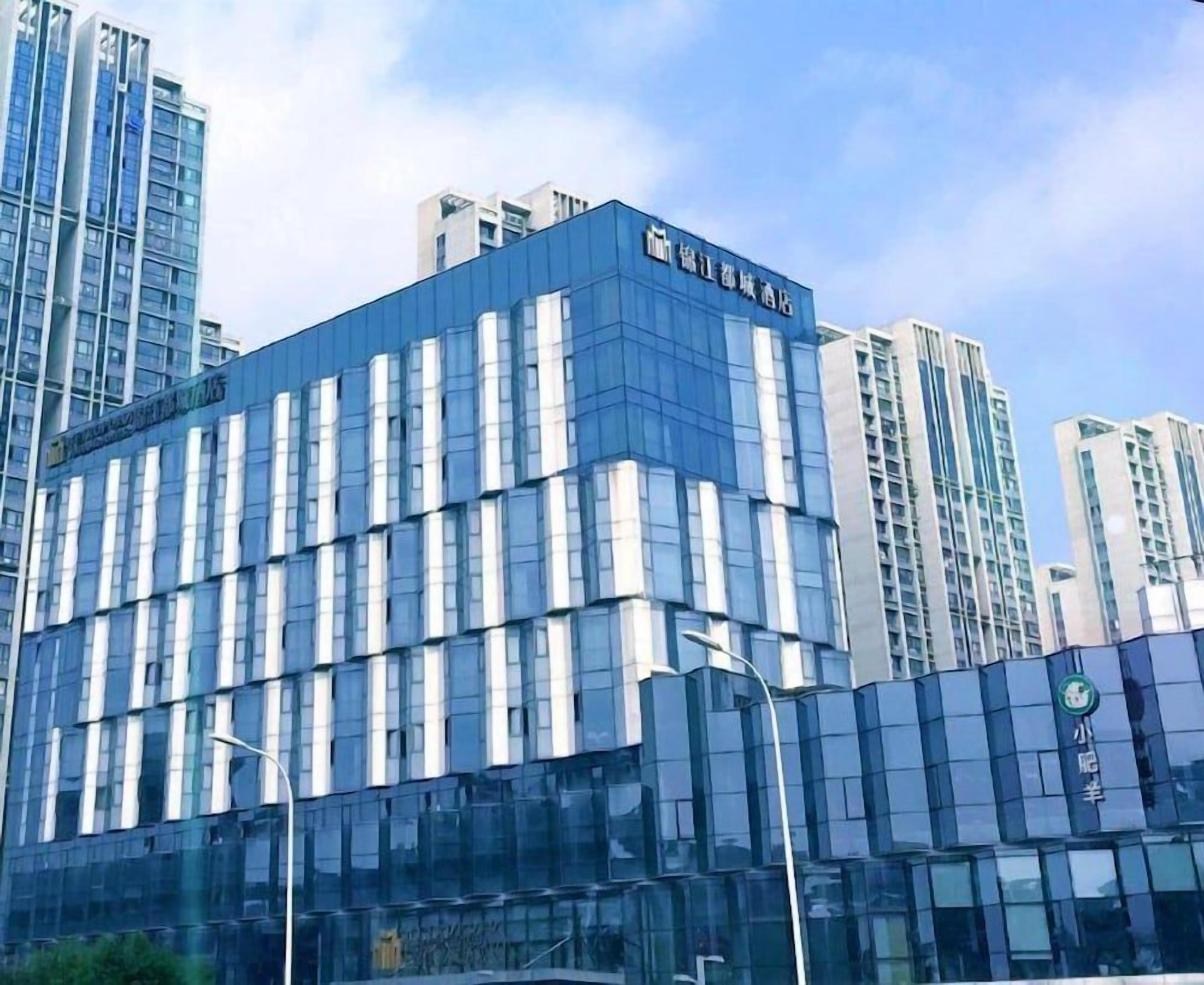 A modern building with a glass facade, featuring a prominent sign at the top.