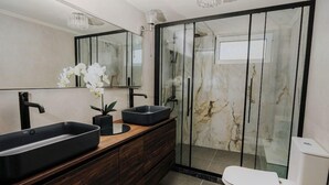 Ein modernes Badezimmer mit einem Doppelwaschtisch, einer Duschkabine aus Glas und einer Toilette.