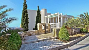 A modern building with a stone entrance, a covered porch, and a view of the sea.