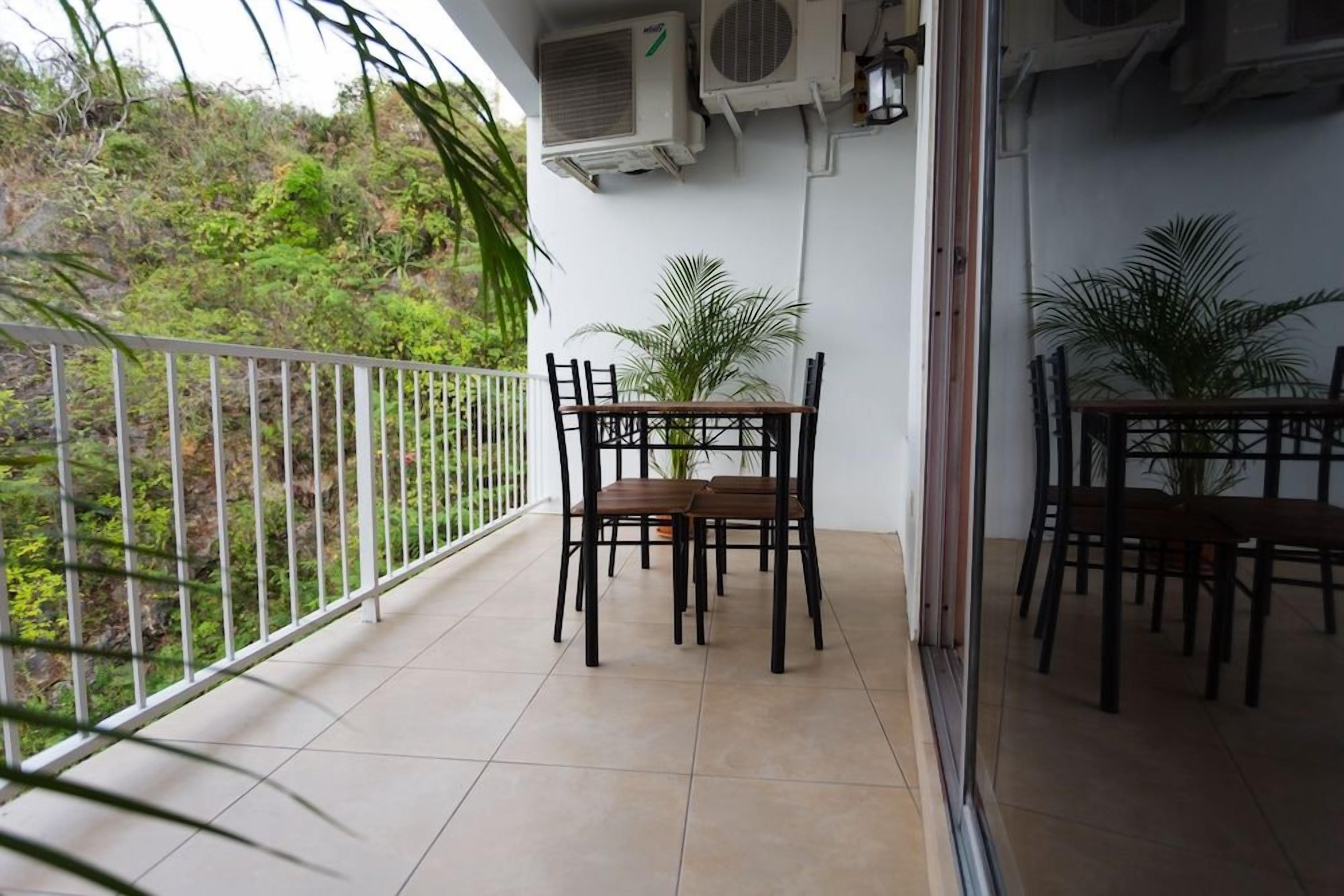Un balcon avec une table et des chaises, des climatiseurs et des plantes en pot.