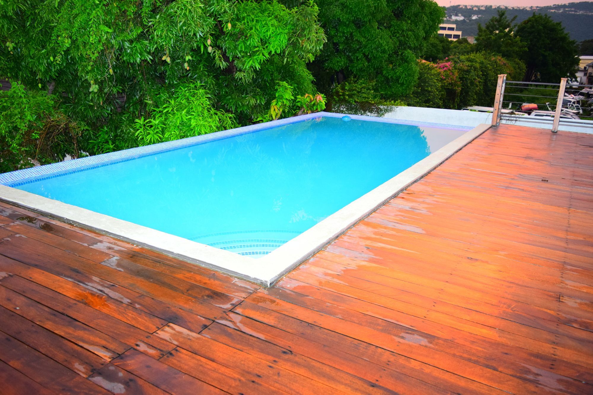 A rectangular swimming pool with a tiled edge, surrounded by a wooden deck.