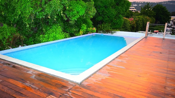 Una piscina rectangular amb un videt de rajola, envoltada per un terra de fusta.