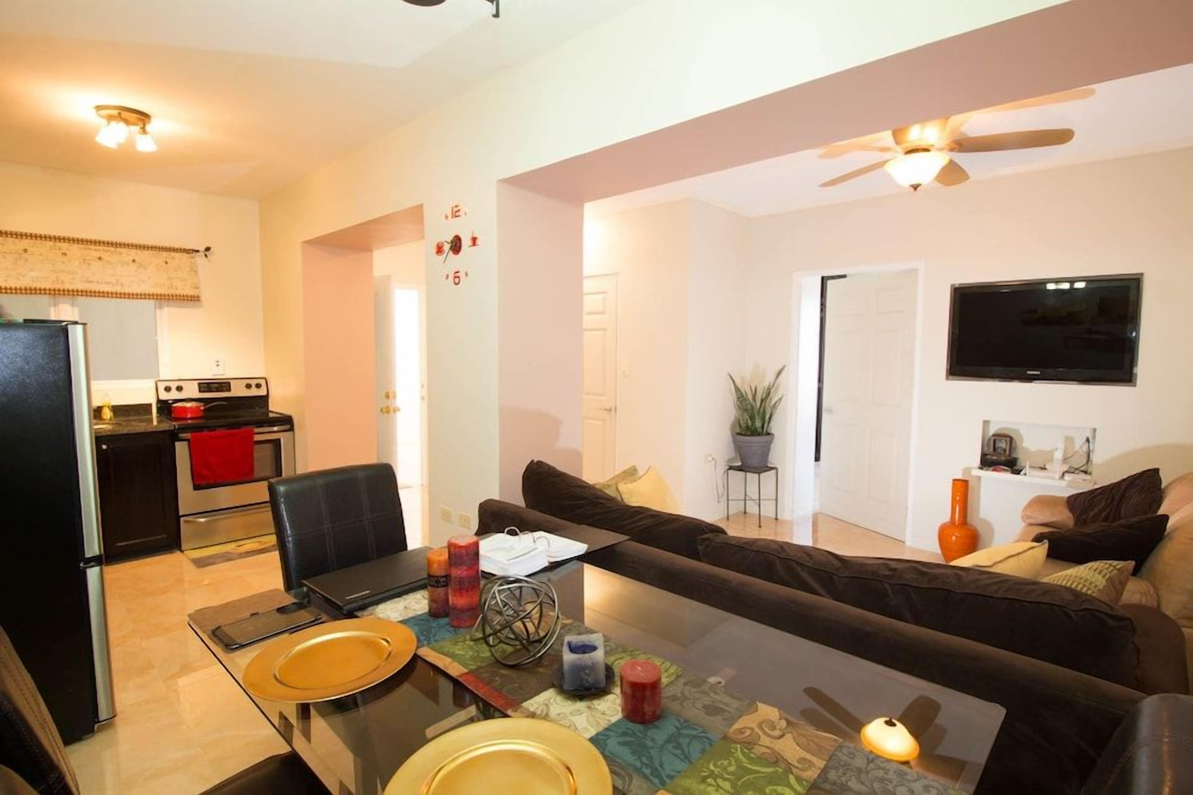 A modern living room with a sofa, a glass coffee table, and a TV mounted on the wall.