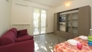 Una sala de estar con un sofá, una mesa de comedor con platos y una botella, y un mueble con puertas de cristal.
