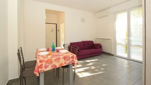 Un comedor con una mesa dispuesta para dos, un sofá rojo y vistas a través de un ventanal.