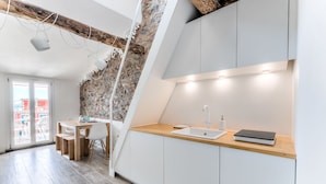 A modern kitchen with a stone wall, a wooden countertop, and a minimalist design. - The First Riomaggiore 5 Terre (Riomaggiore)