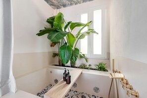Een badkamer met een bad, een raam en een plant.