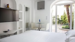 Habitació d'hotel amb llit, televisió, taula petita amb cadires i vista cap a l'exterior.