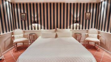 Camera d'albergo con un letto grande, due poltrone, un tavolino rotondo e una parete a righe.