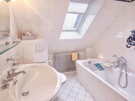 Ein modernes Badezimmer mit einer freistehenden Badewanne, einem großzügigen Waschbecken und einem Oberlicht.