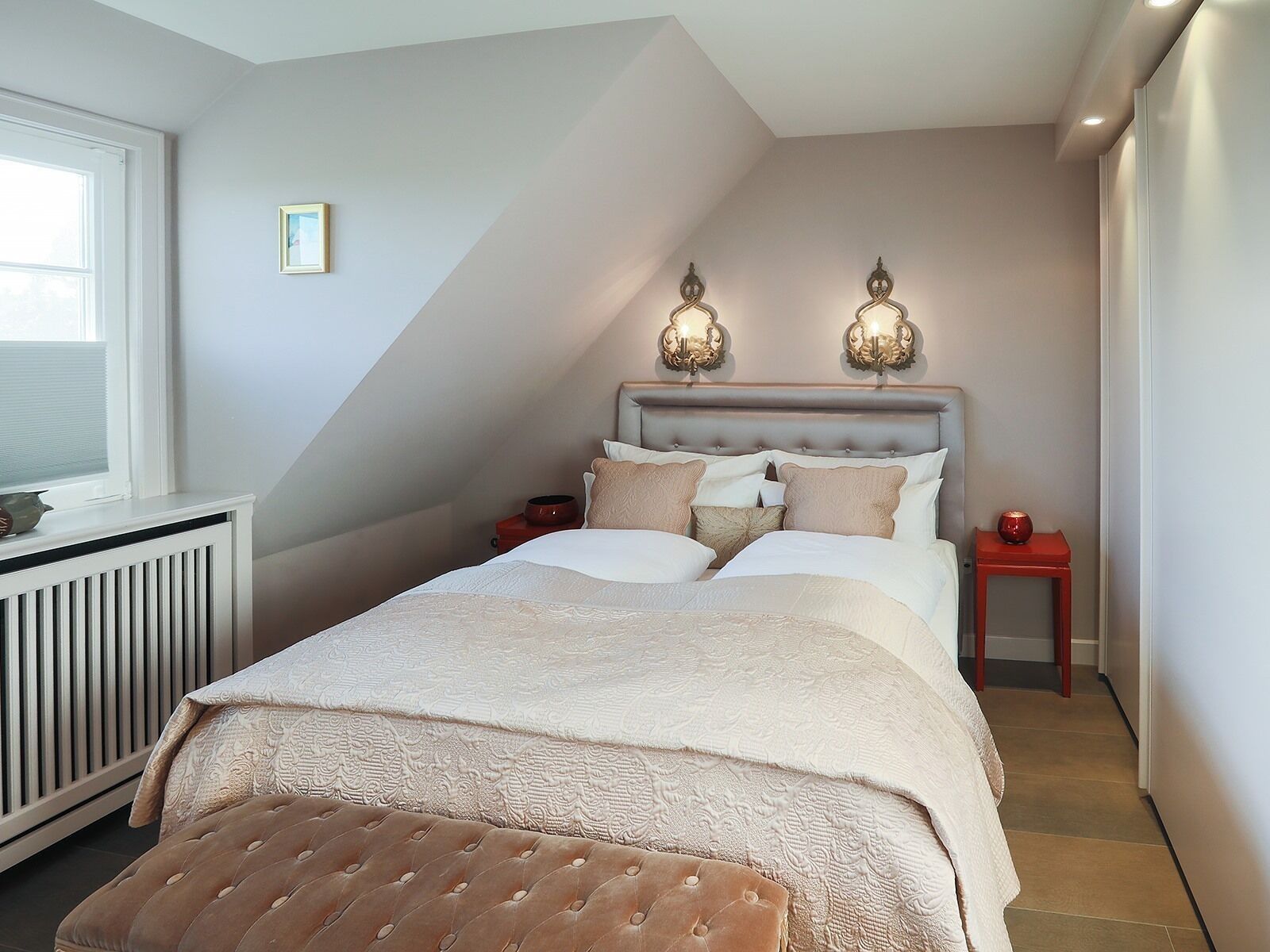 Una camera da letto con un letto, due comodini, un termosifone e una finestra.