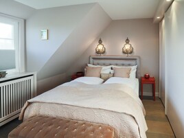 Ein Schlafzimmer mit einem Bett, zwei Nachttischen, einer Heizung und einem Fenster.