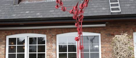 Uma casa com fachada de tijolos, grandes janelas e uma escultura vermelha em frente.