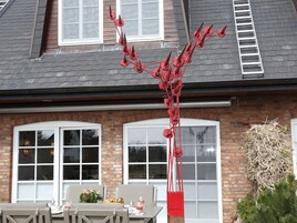 Ein Haus mit Ziegelvorfront, großen Fenstern und einer roten Skulptur davor.