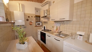Cocina compacta con microondas, estufa, pileta y alacenas blancas.